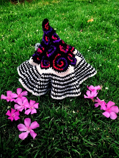 [Los duendes descubrieron a los gnomos estelares, hicieron fiestas y bailes adoptando nuevas costumbres que luego los llevarían a crear el gorrito estelar, basado en todo lo que aprendieron de los gnomos. Las líneas negras y blancas representan las líneas de tiempo reveladas y las que aún están veladas, sus redondelas moradas y fucsias son los distintos universos en constante movimiento y unidos por la vida.] Gorrito Estelar 